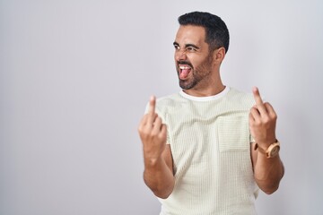Hispanic man with beard standing over isolated background showing middle finger doing fuck you bad expression, provocation and rude attitude. screaming excited