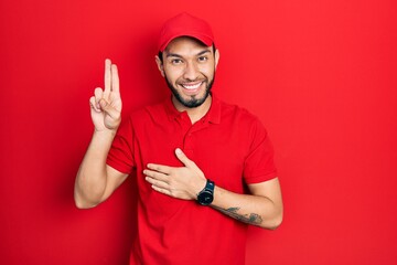 Hispanic man with beard wearing delivery uniform and cap smiling swearing with hand on chest and...