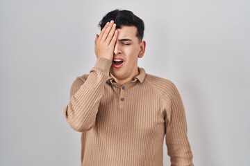 Non binary person standing over isolated background yawning tired covering half face, eye and mouth with hand. face hurts in pain.