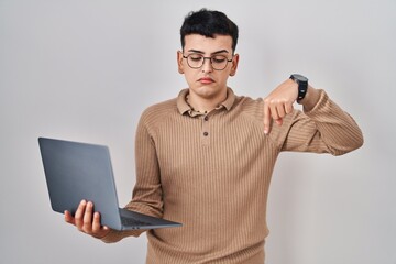 Non binary person using computer laptop pointing down looking sad and upset, indicating direction with fingers, unhappy and depressed.