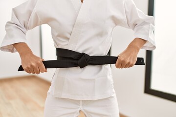 Young caucasian woman tying black karate belt at sport center