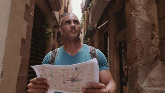 Happy male tourist maps user walking in old town alley an using a map. Barcelona, Spain. Cinematic 4K
