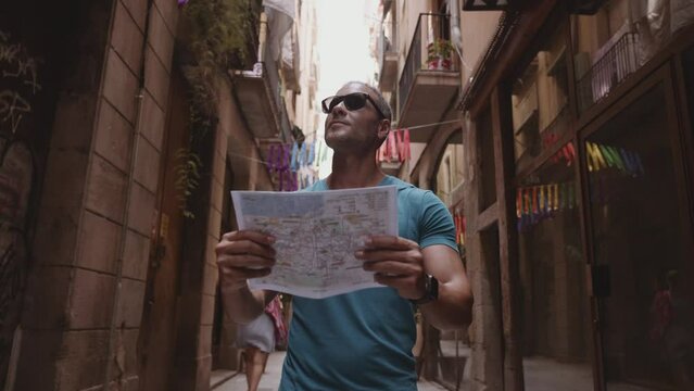 Happy male tourist maps user walking in old town alley an using a map. Barcelona, Spain. Cinematic 4K