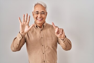 Hispanic senior man wearing glasses showing and pointing up with fingers number six while smiling confident and happy.