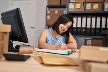 Down syndrome woman ecommerce business worker writing on paperwork at office