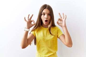 Young brunette teenager standing together over isolated background looking surprised and shocked...