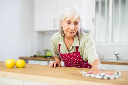 Positive retired woman keeping house clean during day, cleaning kitchen countertop with rag