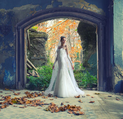 Beautiful bride standing in the old ruined building on autumn day
