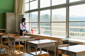 窓際で外を見る女子高生