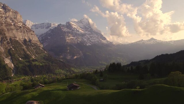 Aerial drone footage dolly left to right revealing moody views of picturesque mountain village in front of eiger north face in swiss alps
