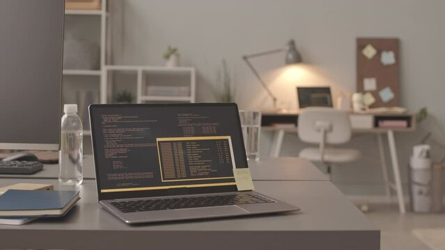 No people slowmo of laptop with program code on screen on desk in bright modern programmers office