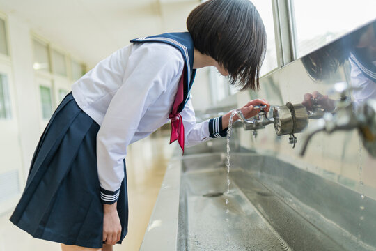 学校 廊下 水を飲む女子高生