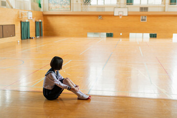 Obraz premium 体育館 ステージに座る女子高生