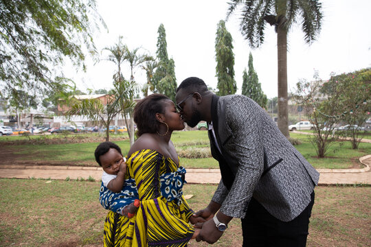 Young african mother with baby on her back kisses her husband. Family concept