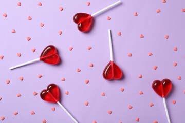 Sweet heart shaped lollipops and sprinkles on violet background, flat lay. Valentine's day...