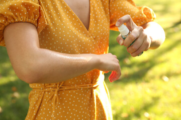 Woman applying insect repellent onto hand in park, closeup - obrazy, fototapety, plakaty