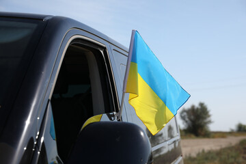 Fototapeta premium National flag of Ukraine on car window outdoors, closeup