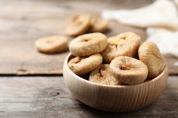 Tasty dried figs in bowl on wooden table