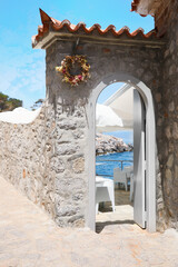 Beautiful seaside terrace with wreath near entrance on sunny day