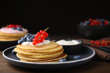 Tasty pancakes with natural yogurt, blueberries and red currants on wooden table. Space for text