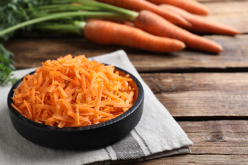 Grated carrot in plate on wooden table