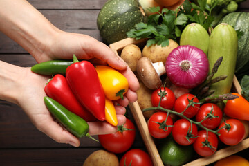 Man holding fresh vegetables at wooden table, closeup