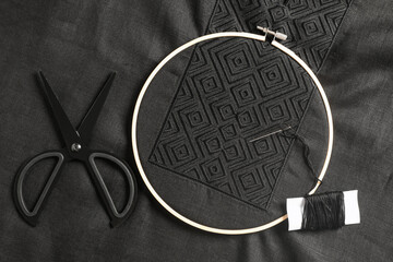 Embroidery hoop, thread and scissors on black shirt, flat lay. Ukrainian national clothes