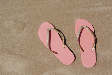 Fototapeta na wymiar Stylish pink flip flops on wet sand, flat lay