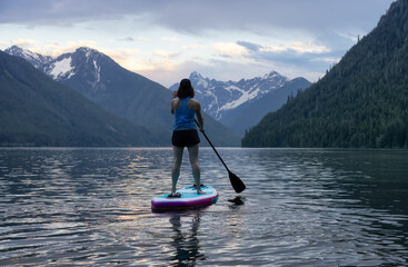 Adventurous Woman Paddle Boarding in a Lake around Canadian Mountain Landscape. Chilliwack Lake, British Columbia, Canada. Adventure Sport Travel