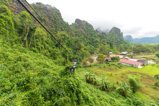 man going on zipline adventure through the forest in Lao
