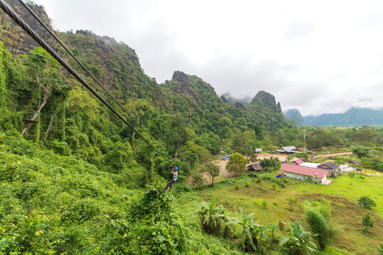 man going on zipline adventure through the forest in Lao