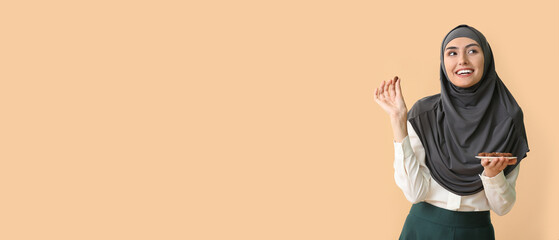 Happy young Arabian woman with chocolate candies on beige background with space for text