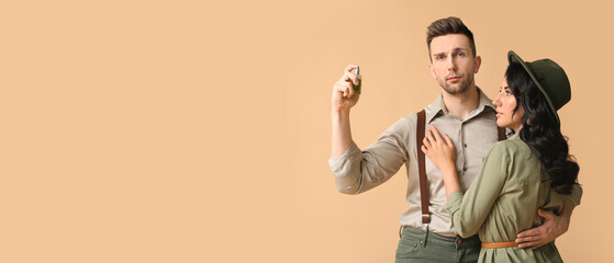 Stylish young couple with perfume on beige background with space for text