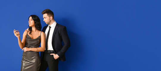 Stylish young couple with perfume on blue background with space for text