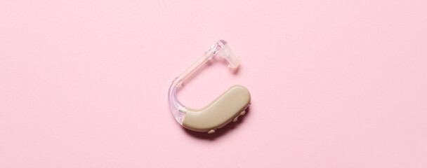 Hearing aid on pink background, top view