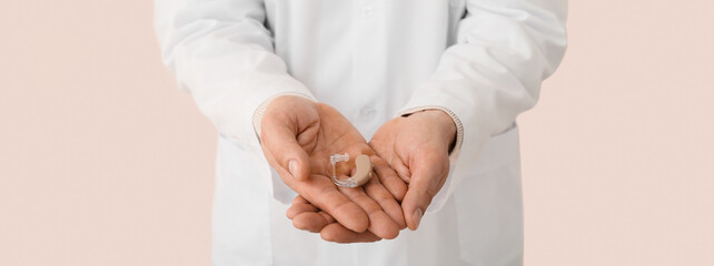 Doctor with hearing aid on light background, closeup
