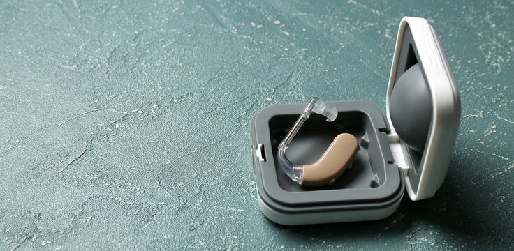 Box with hearing aid on grey background with space for text