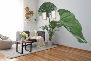 Interior of beautiful light living room with print of monstera leaves on wall