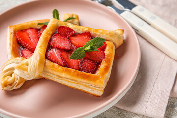 Plate with strawberry puff pastry and mint leaves on table, closeup