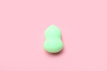 Green makeup sponge on pink background