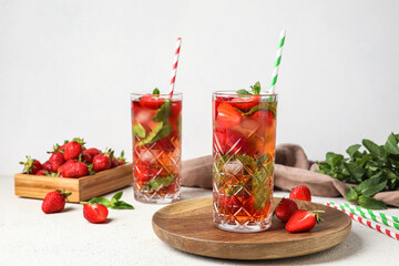 Wooden board with glass of strawberry lemonade on white background