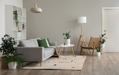 Interior of light living room with grey sofa, table and armchair