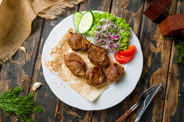 skewers of mutton flesh with red onion on white plate top view on old wooden table