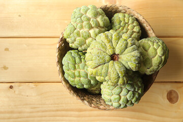 Fresh Sugar Apple fruit, Custard apple, Annona, sweetsop in basket on wooden table. empty space for text.