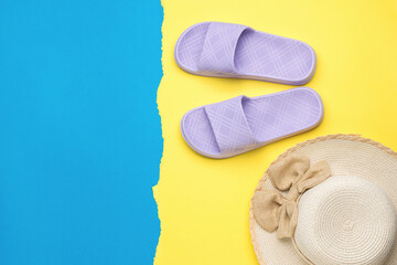 A sun hat and purple flip-flops on a yellow and blue background. The concept of a holiday by the sea.