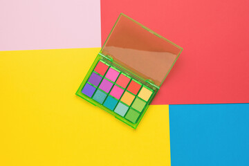 A large set of multi-colored eyeshadow on a multi-colored background. Flat lay.