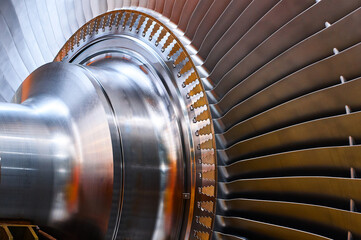 Shiny rotor of powerful steam turbine in light workshop