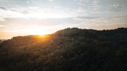 Aerial view on the orange sky, sunset sun and clouds near the tropical jungle in Malaysia.