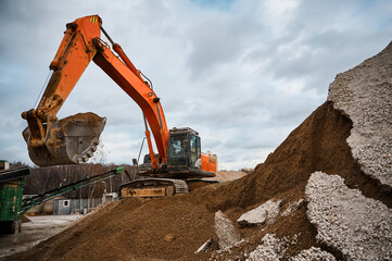 Excavator digs soil with bucket at construction site