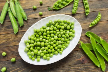 Peeled green peas in a white bowl. Kitchen scene.